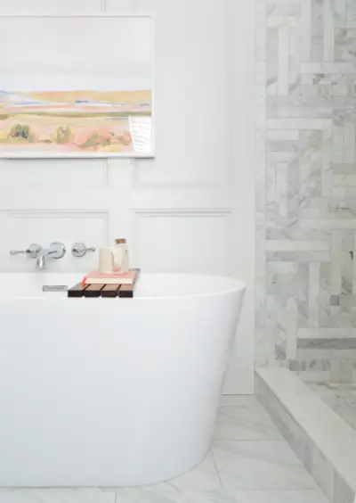 Baignoire autoportante à côté d'une douche en marbre dans la rénovation d'une salle de bains traditionnelle moderne