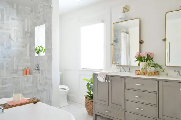 Salle de bain en marbre avec douche à l'italienne en carrelage à chevrons, double meuble-lavabo gris et miroirs pivotants en laiton