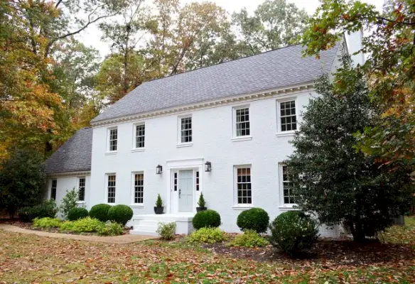 après photo d'une maison en brique peinte en blanc moderne dans le feuillage d'automne