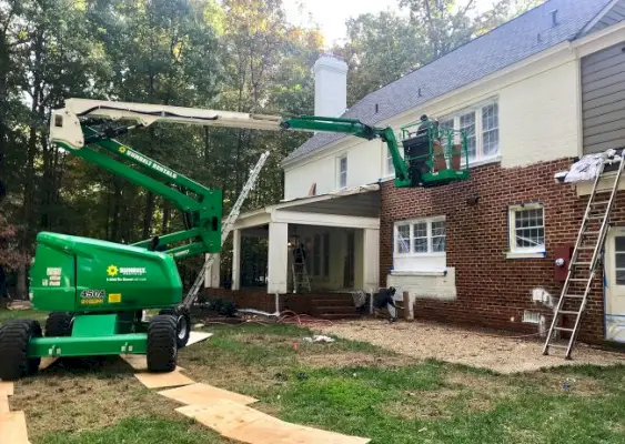 Gran grúa utilizada para pintar la parte trasera de una casa de ladrillo de blanco