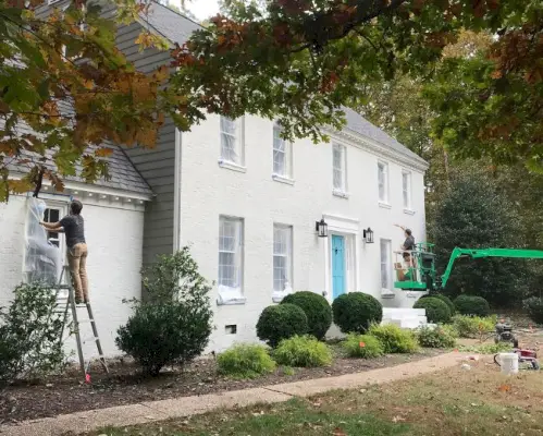 Peintres appliquant une deuxième couche de peinture Romabio Biodomus sur une maison en brique