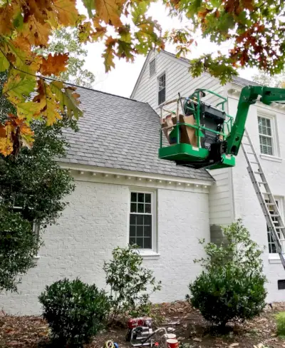 Peintre en peinture de grue parement d'une maison en brique blanche