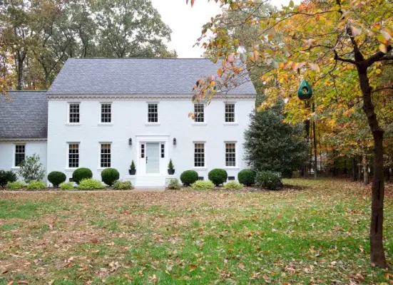 maison en brique peinte en blanc avec congé d'automne et porte bleue tranquillité