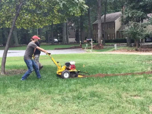 usando a ferramenta valetadeira para cavar o sistema de irrigação no jardim da frente