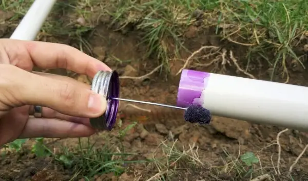 application d'un apprêt violet sur un tuyau en PVC du système d'irrigation