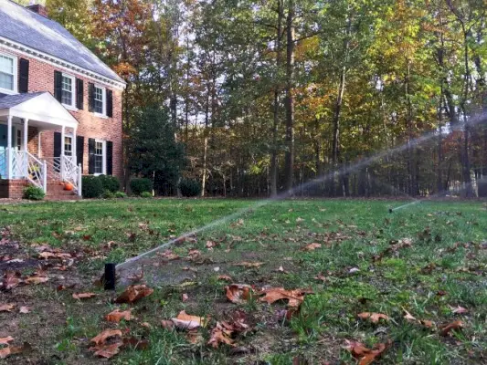 Installatie van irrigatiesysteem waarbij gras in de voortuin wordt teruggegroeid. Sprinklerkoppen ingeschakeld