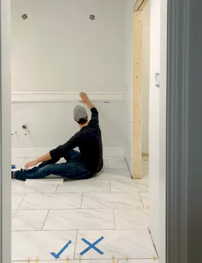 John sosteniendo una pieza de prueba de moldura de pared en el baño