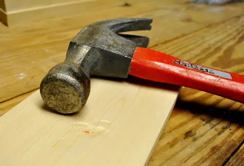 Golpear con un martillo una nueva tabla de madera blanca para que parezca vieja, desgastada y recuperada.