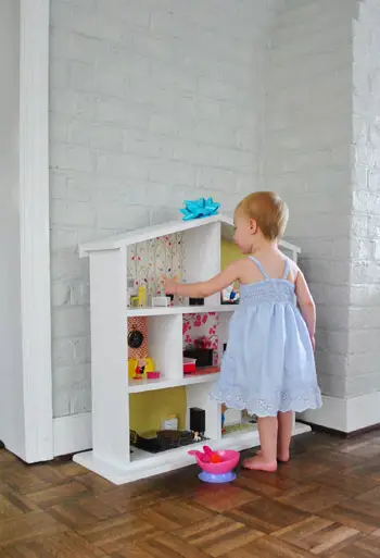 Petite fille jouant avec une maison de poupée réalisée par ses parents