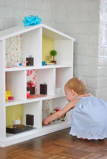 Petite fille jouant avec une maison de poupée DIY facile à réaliser