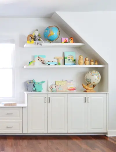 Étagères flottantes blanches dans la salle de jeux avec des jouets sur des armoires de rangement