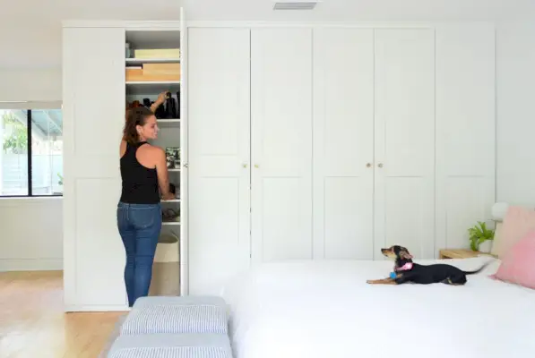 Sherry abrindo guarda-roupa Ikea Pax com Penny Chihuahua na cama