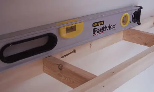 fissaggio della struttura in legno alla parete utilizzando la livella per scaffali sospesi fai-da-te