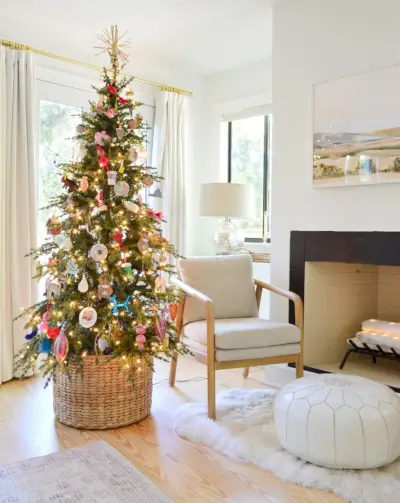 Faux sapin de Noël mince dans un panier tissé à côté d'une chaise et d'une cheminée modernes