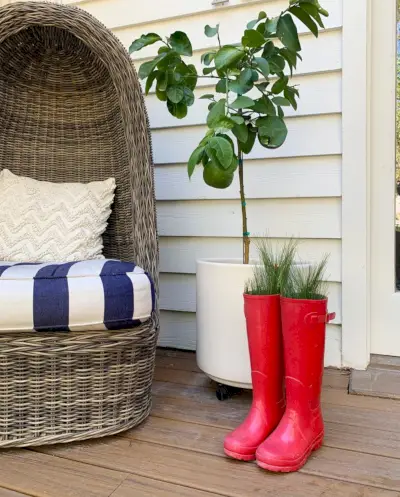 Bottes en caoutchouc rouge avec des branches de faux sapin qui en sortent sur le porche des fêtes