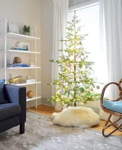 Sapin de Noël clairsemé en faux sapin à côté d'une bibliothèque moderne