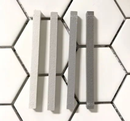 quatro amostras de argamassa mapei em cima de ladrilho hexagonal branco indo do claro ao escuro