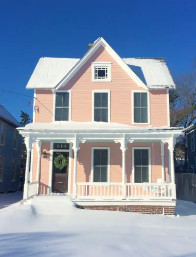 Casa de playa rosada histórica cubierta de nieve