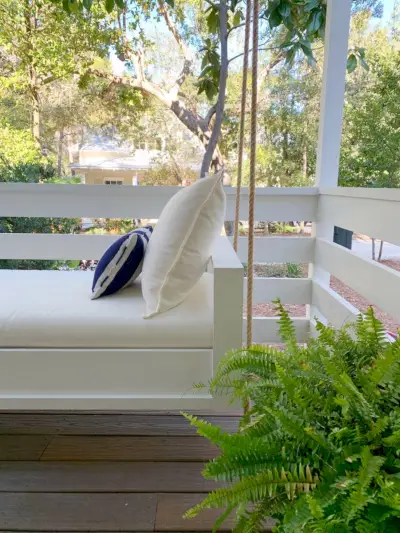 Vue latérale du lit de repos suspendu blanc fini avec coussin crème