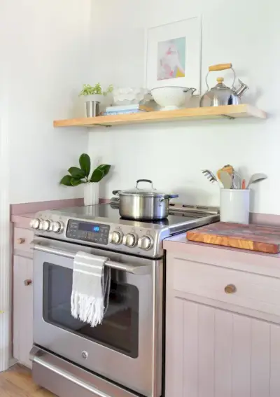 Cuisinière électrique en acier inoxydable avec armoires mauves et étagère en bois flottante