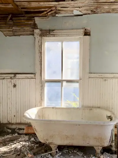 Vóór de foto van de badkamer van een strandhuis met afbrokkelende muren en een vuile badkuip