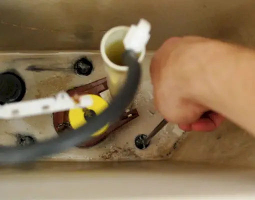 Main avec tournevis boulons de réglage dans le réservoir des toilettes