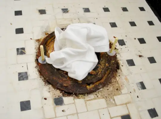 Nouveaux boulons sur la bride des toilettes avec un chiffon dans le trou d'égout