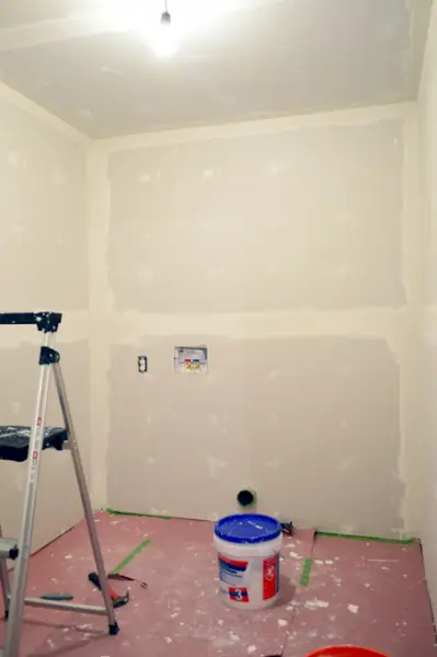 sala pequena com uma camada de fita de drywall e lama aplicada