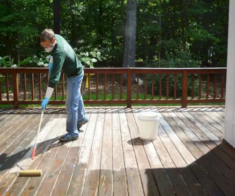 John brengt dekstripper aan op een houten terras in de zon