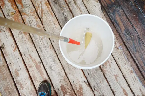 Tremper le rouleau à peinture dans le seau de détachant pour terrasse