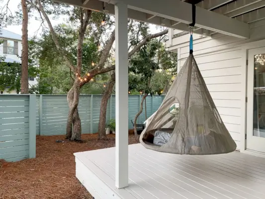 Twee kinderen liggen in een hangende tent op een overdekte veranda