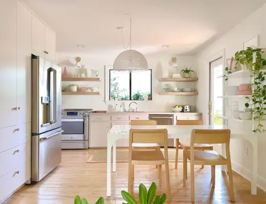 Cocina pequeña con gabinetes blancos y malva con plantas.