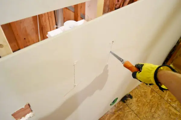 utiliser une scie à cloison sèche pour percer un trou pour la plomberie de la lessive dans une feuille de cloison sèche