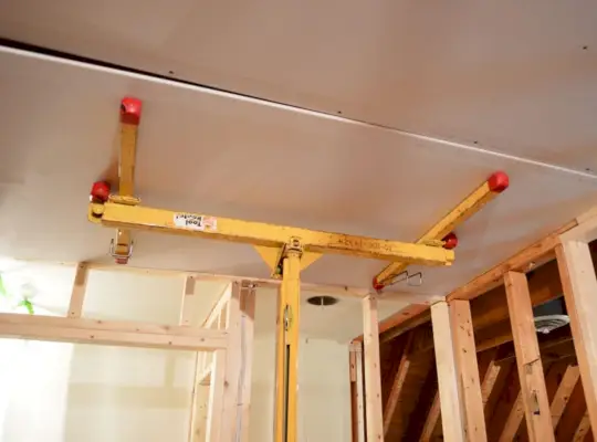 sheetrock panel holdt mod loftet af vaskerum ved hjælp af gipsvæg lift