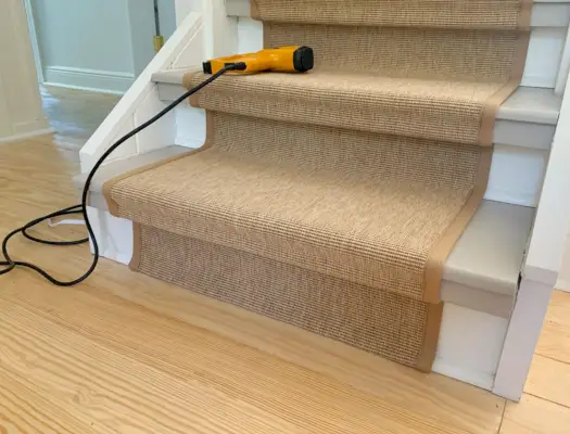 Marche inférieure de l'escalier montrant l'extrémité pliée du coureur d'escalier en sisal