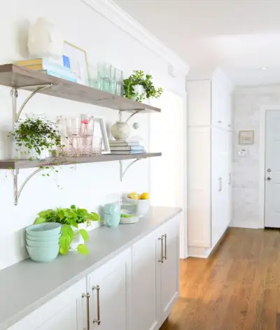 Étagères en bois récupéré avec supports en nickel poli dans une cuisine blanche