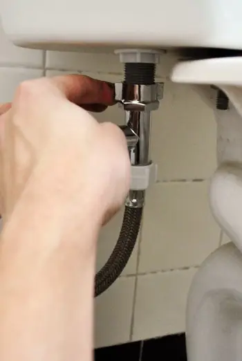 Rebrancher la conduite d'alimentation en eau sous le réservoir des toilettes