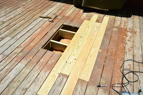 Trou réparé dans une terrasse en bois avec de nouvelles planches