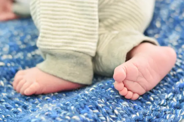 Foto neonatale fai da te dei piedini del neonato su una coperta blu per l'annuncio di nascita