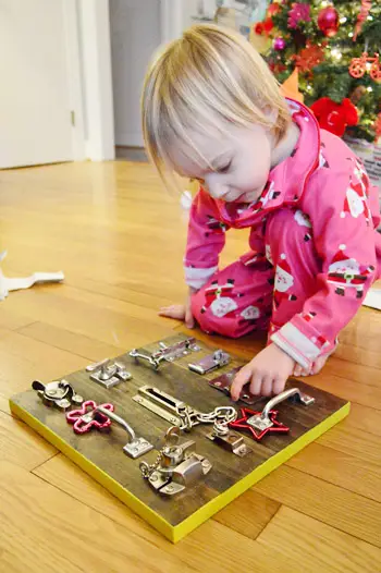 Una tabla ocupada de bricolaje con pestillos para niños