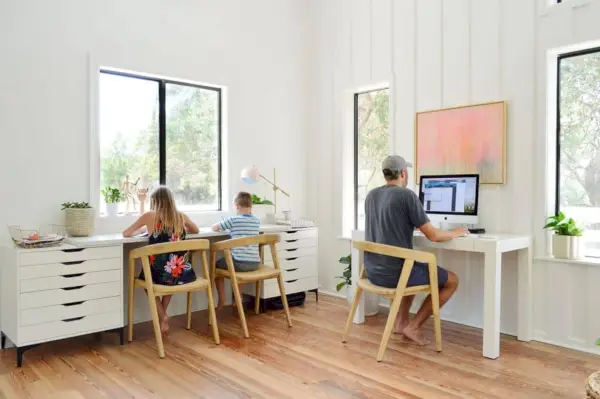 Crianças trabalhando na mesa de arte com John na mesa de escritório