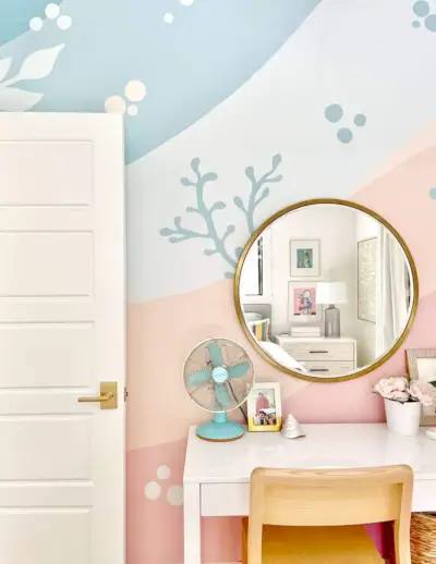 Chambre de filles colorée avec fresque murale de plage en corail rose bleu avec miroir doré sur le bureau