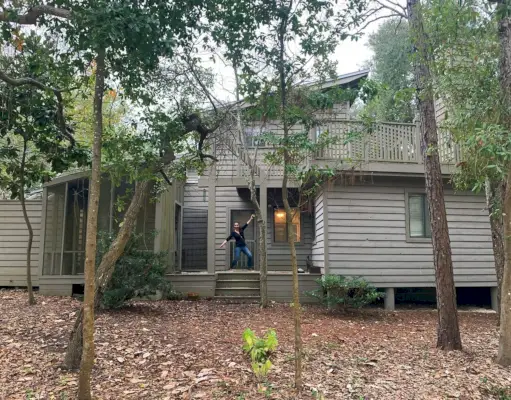 Avant la photo d'une maison avec un revêtement marron et une cour en terre battue couverte de feuilles