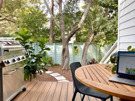 Vista del porche de la cocina con parrilla al aire libre y mesa con computadora portátil