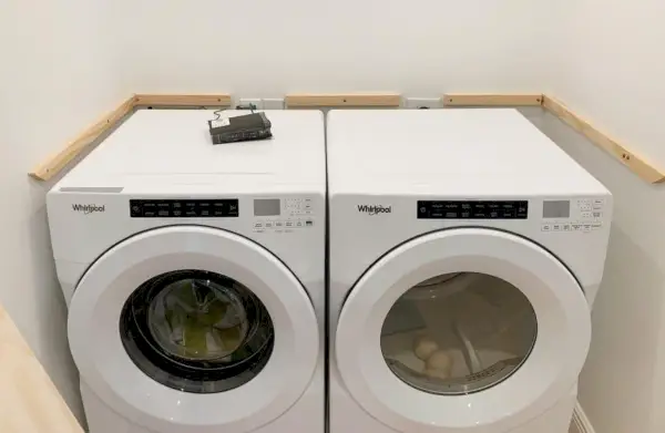 Supports d'étagères à linge en bois ajoutés aux murs en plus de la laveuse et de la sécheuse