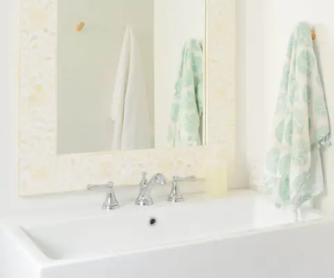 Salle de bains moderne et lumineuse avec grand lavabo blanc et miroir incrusté d'os