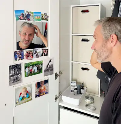 John macht sich im Schrankspiegel im Ikea-Pax-Kleiderschrank fertig