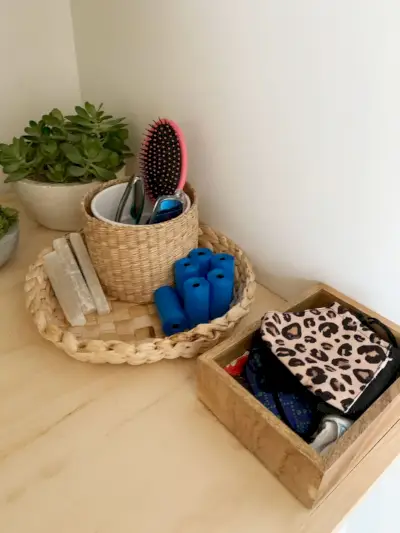 Cestas e recipientes na prateleira da lavanderia contendo acessórios de entrada, como máscaras, bolsas para cães e óculos de sol