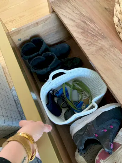 Tiroir ouvert de la table basse de rangement en bois montrant des chaussures et un panier avec des clés