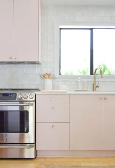 Vista verticale dei mobili da cucina Ikea dipinti di rosa malva con alzatina in piastrelle grigie